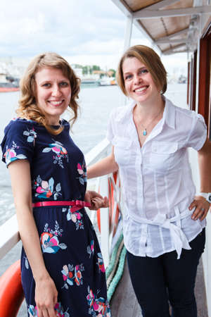 Happy attractive women standing on ship deck during sea cruiseの写真素材