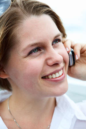 Happy woman in white shirt with sunglasses calling on mobile phone. Close upの写真素材