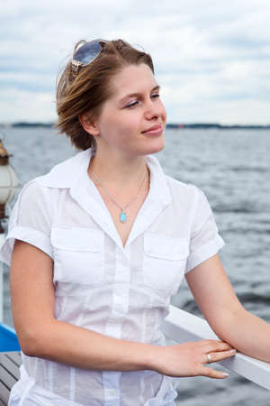 Woman in white shirt with sunglasses standing on vessel deck near railsの写真素材
