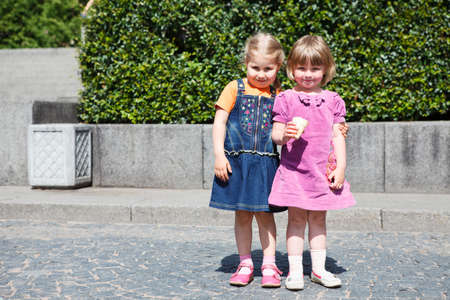 Two sweet little girls standing together with one ice cream  Copyspace
