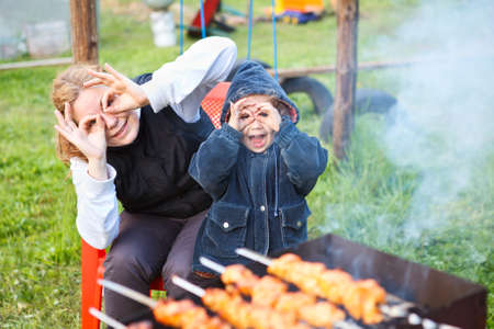 Mother and little daughter making faces during cooking meatの写真素材