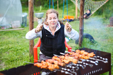 Hangry young female with fork and knife in hands sitting and waiting for grill meatの写真素材