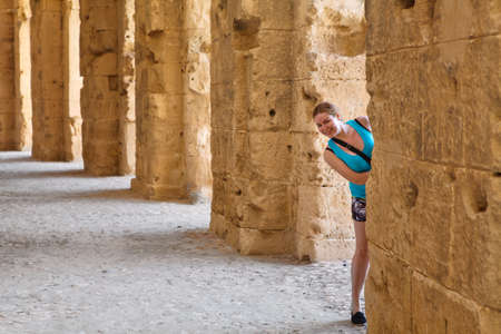 Young woman looking from column in demolished ancient walls and arches in Tunisian Amphitheater in El Djem, Tunisiaのeditorial素材