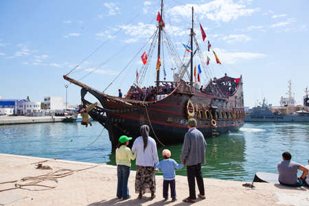 SOUSSE, TUNISIA - CIRCA MAY, 2012: Out at heels Tunisian family standing on Sousse city pier and looking at vessel on circa May, 2012 in Sousse, Tunisia.のeditorial素材