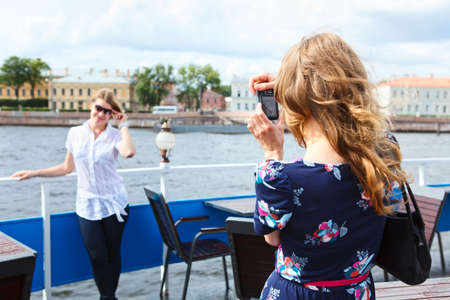 Woman photographer photographing her girlfriend with hand-held cameraの写真素材