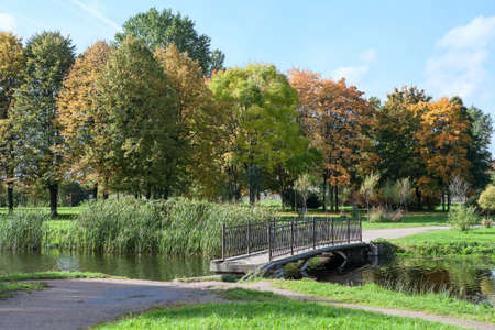 Old footbridge across pond in the autumn parkの写真素材