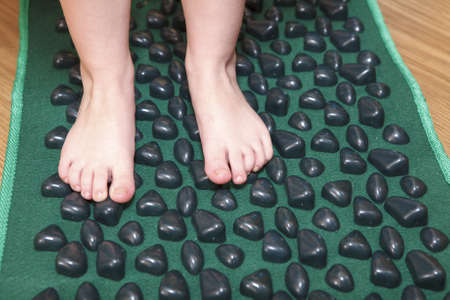 Children little feet standing on massage mat for flatfoot treatmentの写真素材