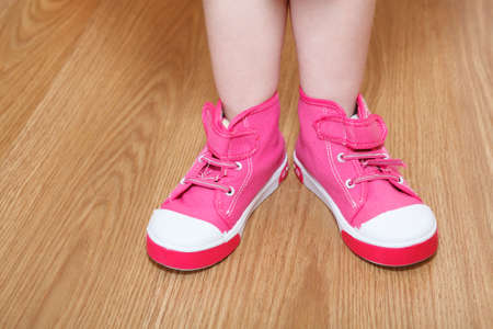Children legs in pink shoes standing on the floorの写真素材