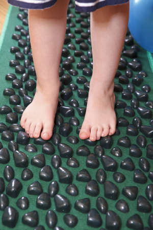 Children feet standing on massage carpetの写真素材