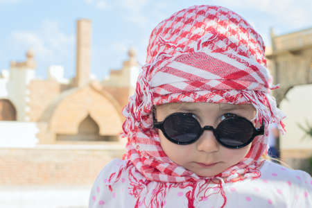 Close-up portrait of beautiful young Caucasian girl in Muslim head kerchief and sunglassesの写真素材