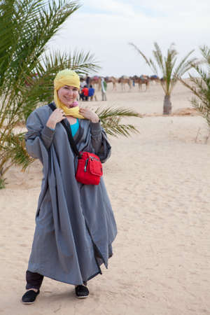 Caucasian woman in bedouin clothes standing on dune in desert