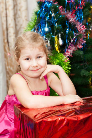 Small girl portrait with gifts near Christmas treeの写真素材