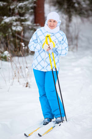 Happy young woman standing on ski with poles in handsの写真素材