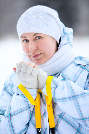 Young smiling woman warming fingers with ski poles in handsの写真素材