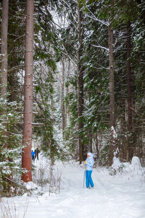 Happy young woman standing on ski in deep winter forestの写真素材