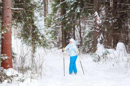 Female skier turning back skiing in winter forestの写真素材