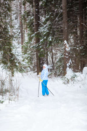 Young woman on ski looking back when skiing in winter forestの写真素材