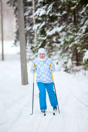 Happy Caucasian woman skiing in wintry forest aloneの写真素材