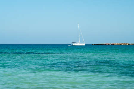 Seashore of Cyprus island with rocky coast and white yacht in Mediterranean sea horizonの写真素材