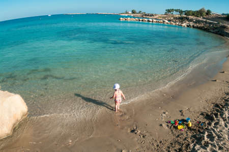 Little Caucasian child playing on sandy beach of Mediterranean sea, Cyprus. Wide angle viewの写真素材