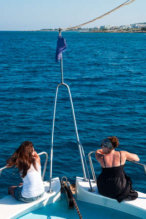 Two brunette women on bow of yacht in Mediterranean sea cruiseの写真素材