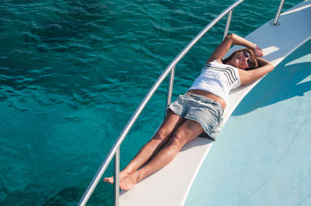 Happy brunette woman laying on shipboard of yacht. Copyspaceの写真素材