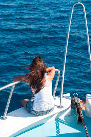 Brunette woman on bow of yacht with legs outの写真素材