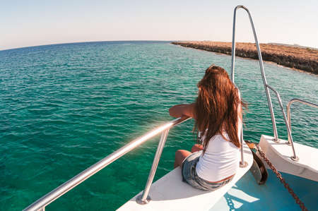 Wide angle view of back sitting woman on shipboard with legs out. Copyspaceの写真素材