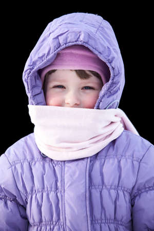 Small Caucasian girl wrapped in winter clothes isolated on black backgroundの写真素材
