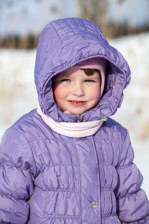 Small Caucasian girl in winter clothes standing outdoorの写真素材