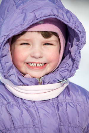 Close-up portrait of small Caucasian girl in winter clothes with hood on headの写真素材