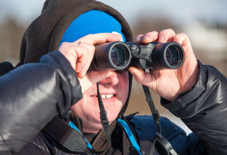 Close up of Caucasian man with binoculars looking far awayの写真素材