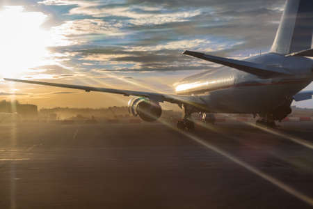 Passenger aircraft standing on runway in sunset sunlightsの写真素材