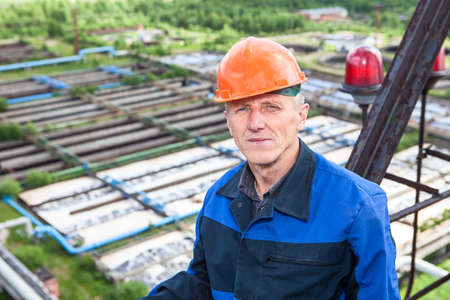 Senior Caucasian manual worker standing against water treatment plantの写真素材