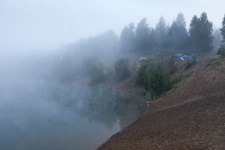 Fog on the lake with standing tourist tents at early morningの写真素材