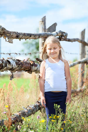 Caucasian small girl with closed eyes standing in front of fenceの写真素材
