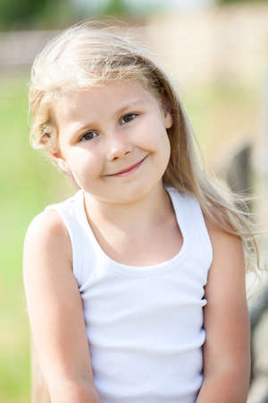 Half-length portrait of beautiful smiling girl with blond hair outdoorsの写真素材