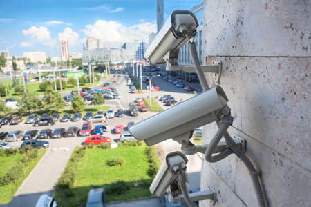 Video surveillance cameras on a wall looking at street parking areaの写真素材