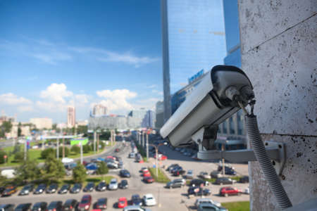 Video surveillance camera on a wall looking at street parking zoneの写真素材