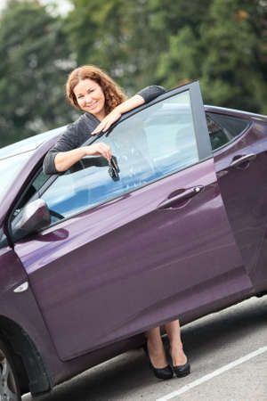 Caucasian brunett young woman near own car with keysの写真素材