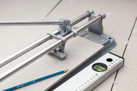 Tile-cutter, building level and tiles on floor の写真素材