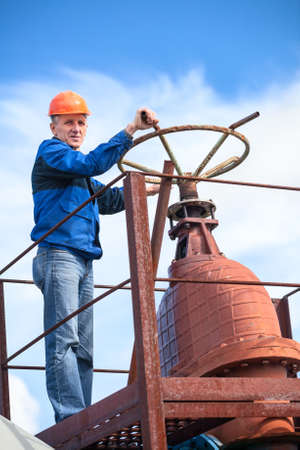 Mature manual worker turning huge valve gate at factoryの写真素材