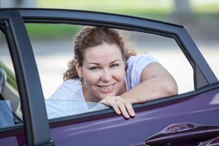 Young joyous beauty woman looking at opened car window in door