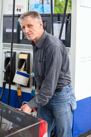 Caucasian mature man refueling car with gasolineの写真素材