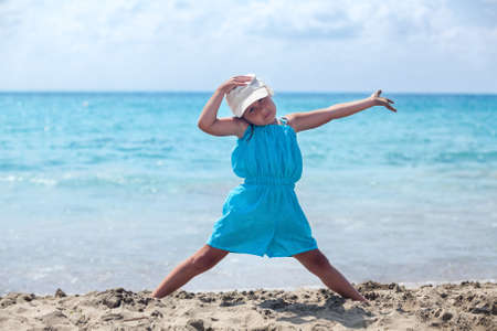 Joyful funny young girl in blue dress standing on sandy sea beachの写真素材