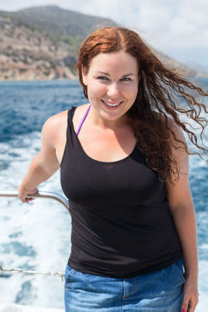 Curly hair young woman in sea cruise on yachtの写真素材