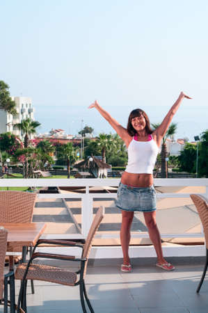 Attractive young woman standing hands up on terrace of houseの写真素材