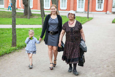 Grandmother, mother and young daughter walking in park at summer season