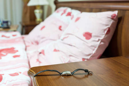 Wristwatch on the bedside cabinet in the bedroom next to the bedの写真素材