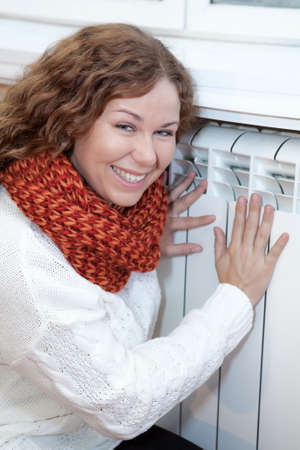 Happy smiling woman touching warm central heating convectorの写真素材